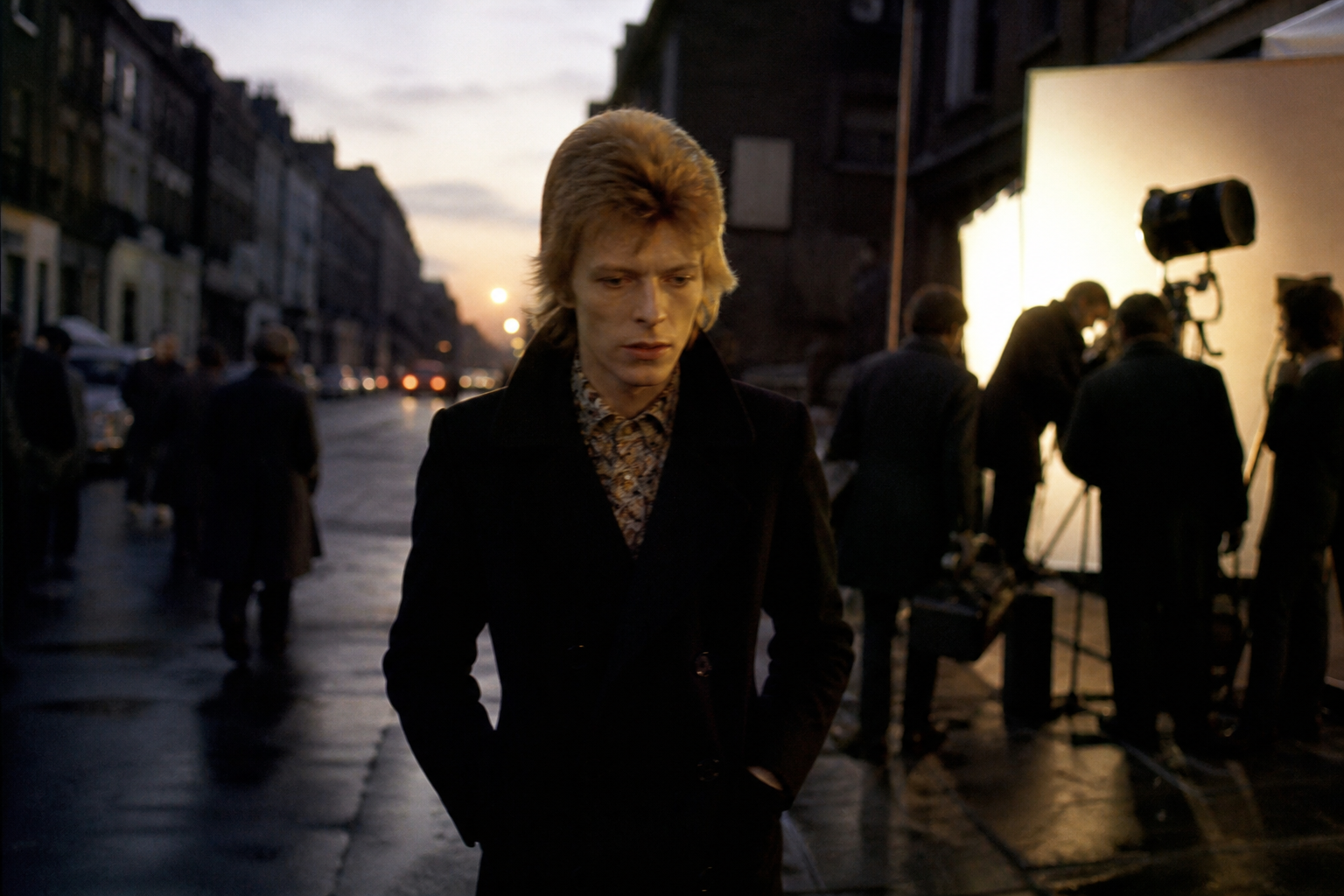 Stylized 1960s London music scene with a young David Bowie figure walking away from a film set